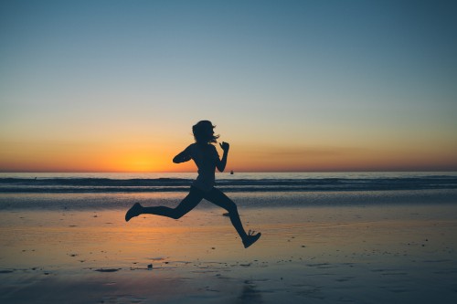 Image silhouette of man jumping on beach during sunset