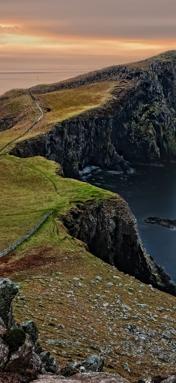 Image green grass covered mountain beside body of water during daytime