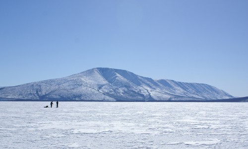 Image person standing on dock near snow covered mountain during daytime