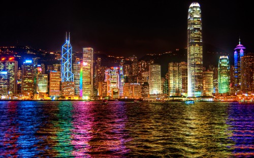 Image city skyline across body of water during night time