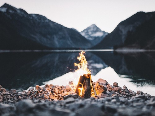 Image bonfire on rocky shore near lake during daytime