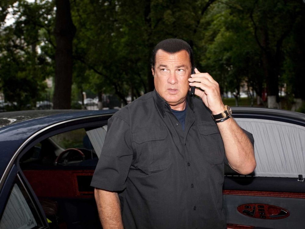 man in black button up shirt standing near red car during daytime