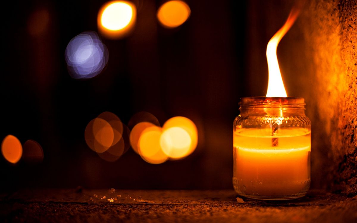 lighted candle in clear glass container