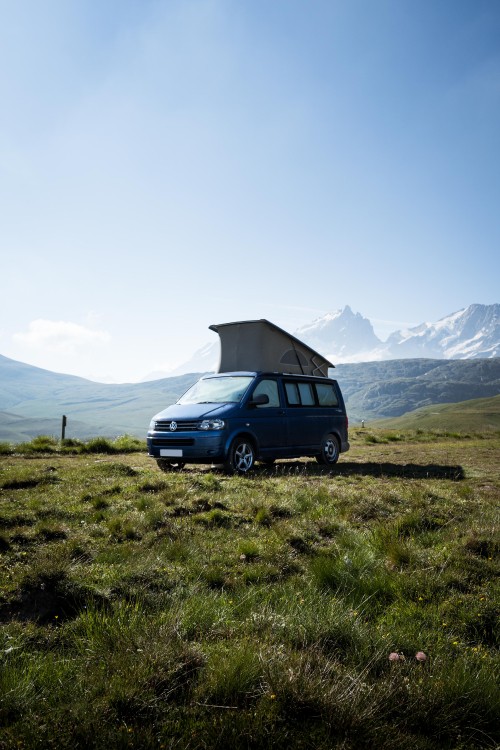 Image blue suv on green grass field near mountain during daytime