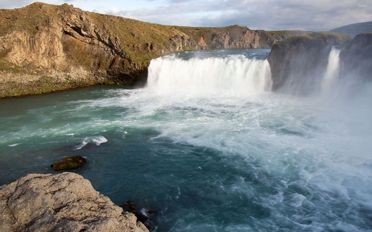 water falls on brown rocky mountain during daytime