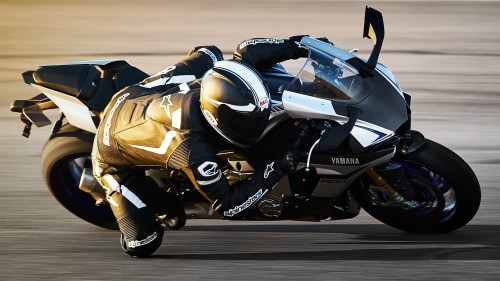 Image man in black and white motorcycle suit riding on white and black sports bike