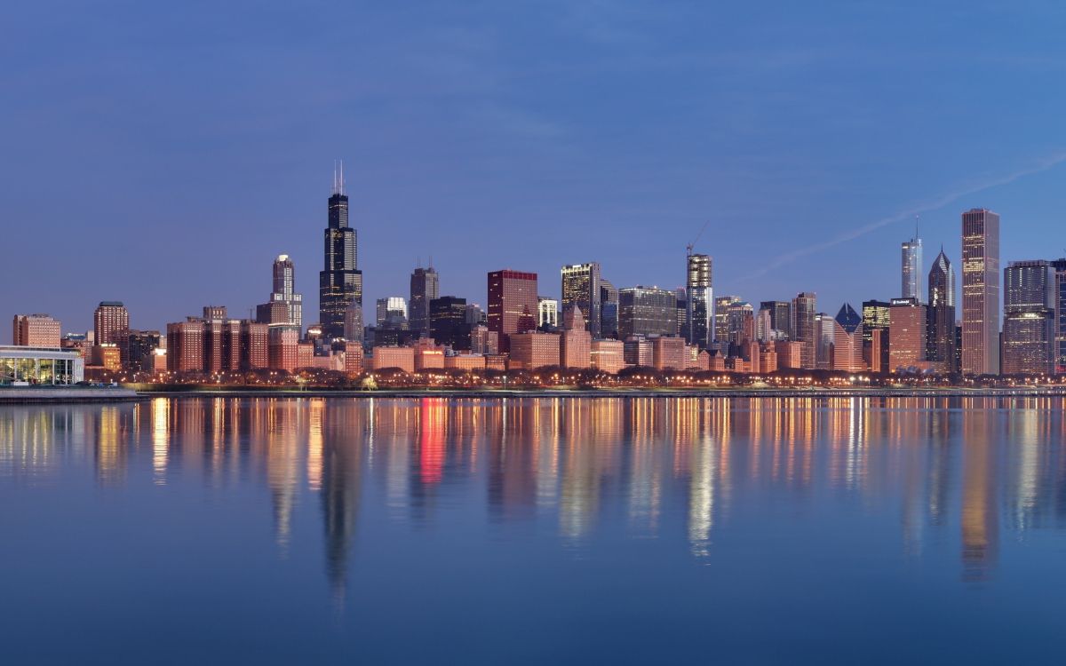 city skyline across body of water during night time