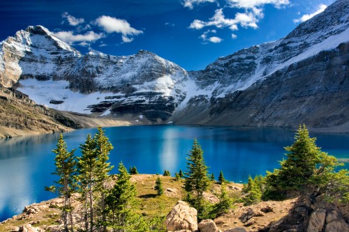 Image lake surrounded by green trees and snow covered mountains during daytime