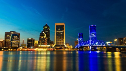 Image city skyline across body of water during night time