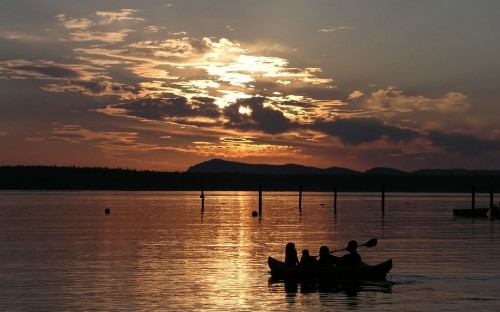 Image silhouette of people riding boat on sea during sunset