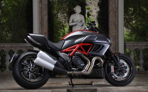 Image black and red sports bike parked beside green plants during daytime