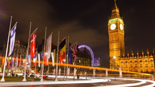 Image brown concrete building with flags during nighttime