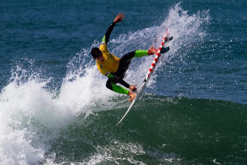 Image man in yellow shirt and black shorts surfing on sea waves during daytime