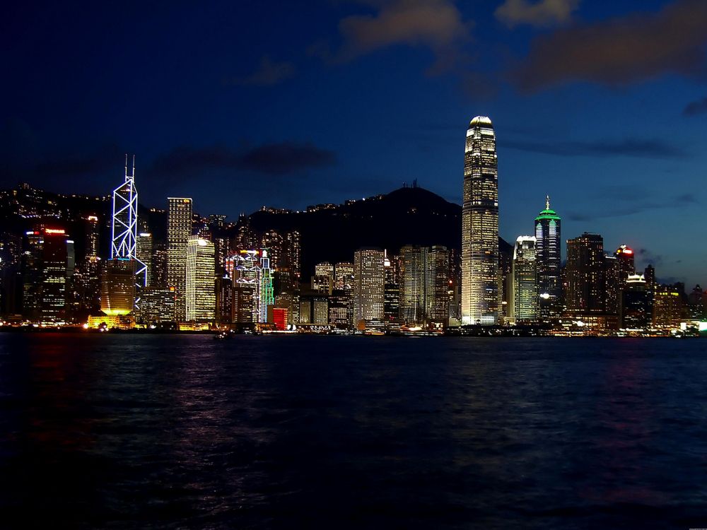 city skyline across body of water during night time