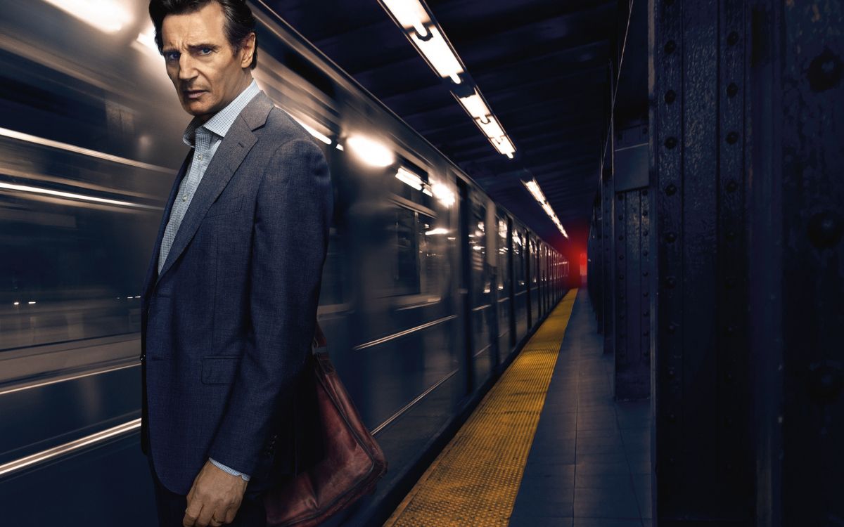 man in black suit standing on train station