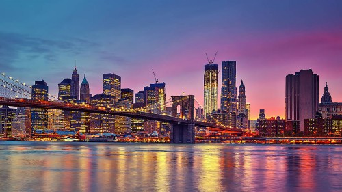 Image city skyline across body of water during night time