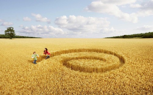 Image 2 people sitting on green grass field under white clouds and blue sky during daytime