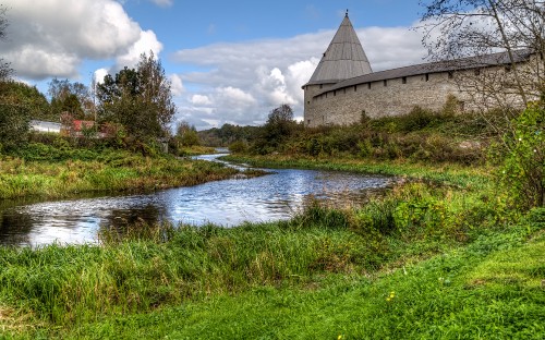 Image brown concrete building near river under white clouds and blue sky during daytime