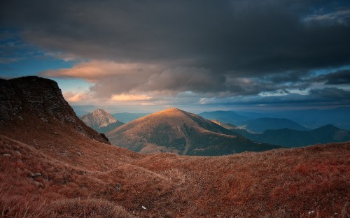 Image brown and green mountains under white clouds and blue sky during daytime