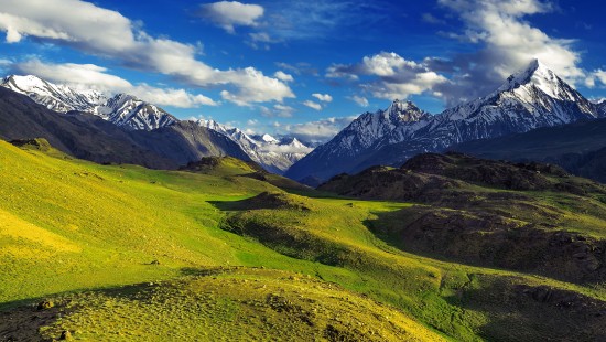 Image green grass field near mountains under blue sky during daytime