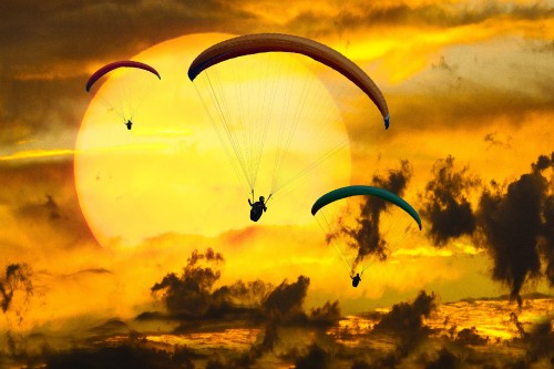 Image silhouette of person riding parachute during sunset