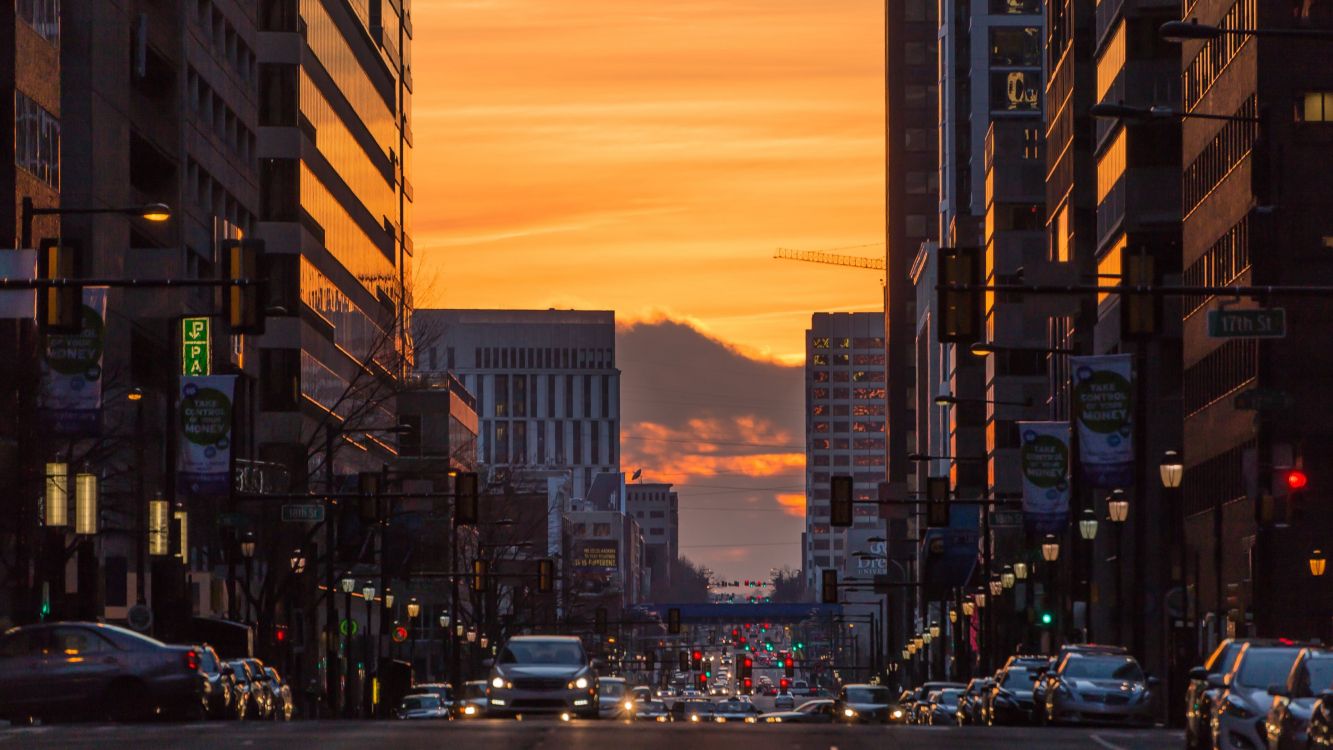 cars on road between high rise buildings during sunset