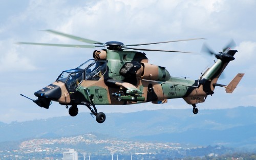 Image green and black camouflage helicopter flying over the clouds during daytime