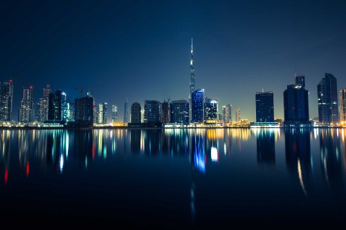 Image city skyline across body of water during night time