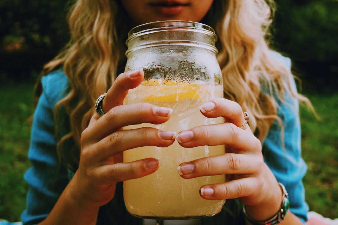 Femme Tenant un Bocal en Verre Transparent Avec du Liquide Jaune. Wallpaper in 4096x2725 Resolution