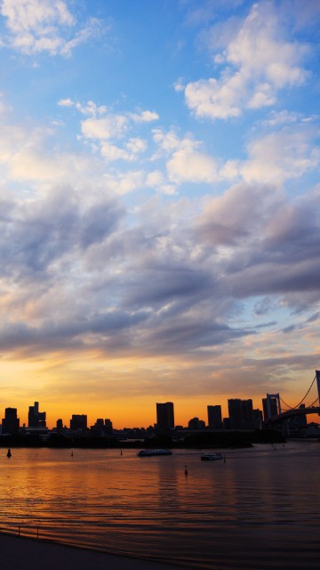 Image silhouette of city buildings near body of water during sunset