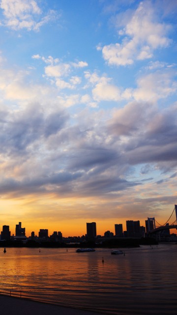 Image silhouette of city buildings near body of water during sunset