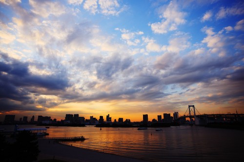 Image silhouette of city buildings near body of water during sunset