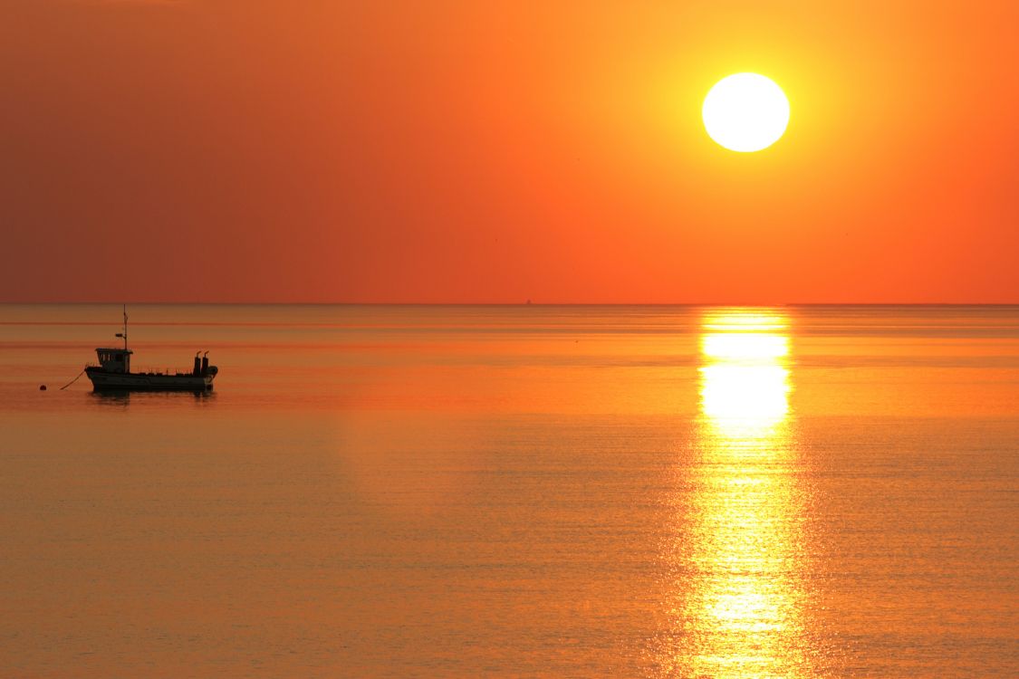 silhouette of person riding boat on sea during sunset