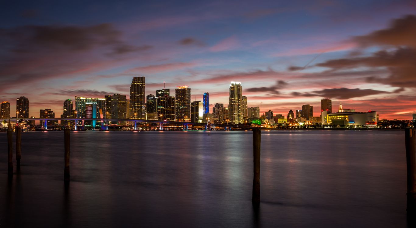 city skyline across body of water during sunset