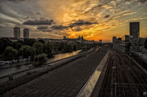 Image train rail near city buildings during sunset