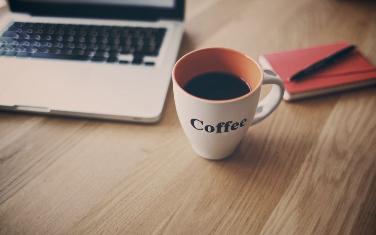 white ceramic mug beside macbook pro