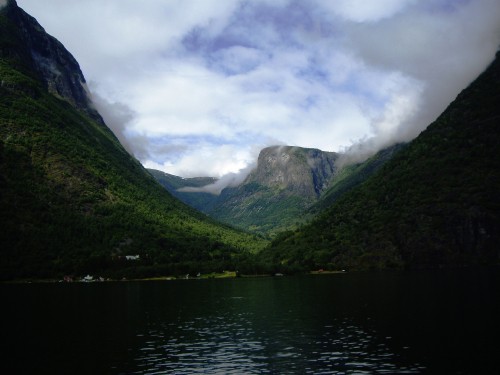 Image green mountains beside body of water under cloudy sky during daytime