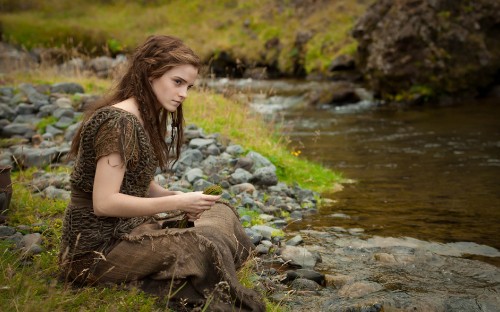 Image woman in brown and black leopard print tank top sitting on rock near river during daytime