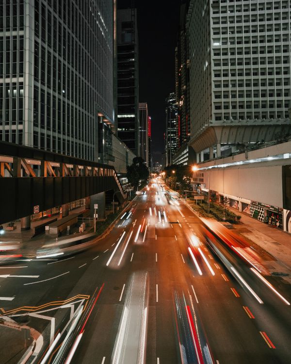 Autos Auf Der Straße Zwischen Hochhäusern Während Der Nacht. Wallpaper in 3888x4860 Resolution