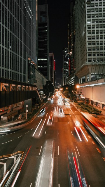 Image cars on road between high rise buildings during night time