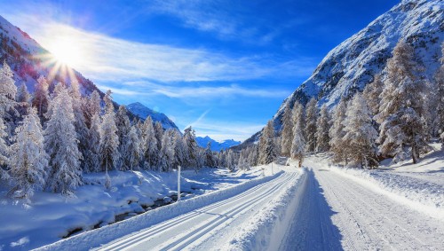 Image snow covered road near mountain under blue sky during daytime