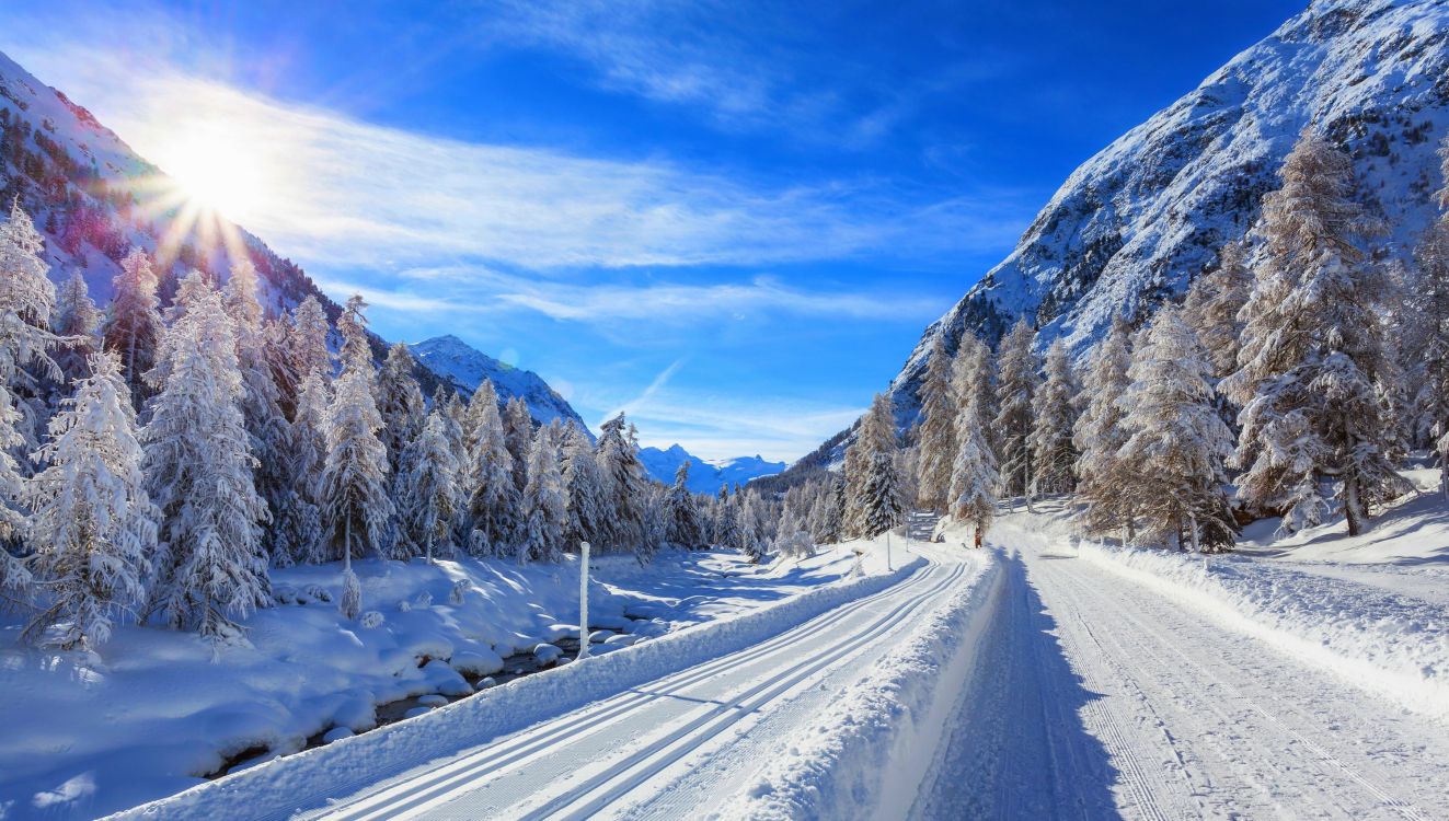 snow covered road near mountain under blue sky during daytime