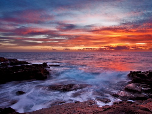 Image ocean waves crashing on rocks during sunset