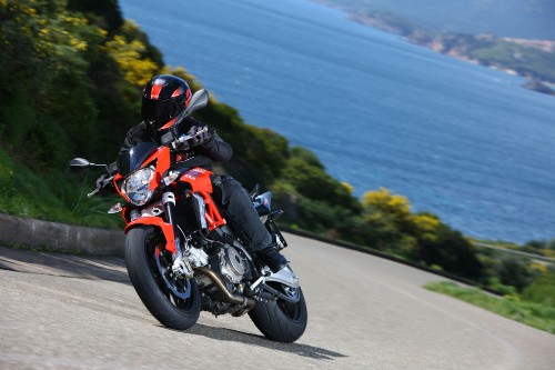 Image man in orange and black motorcycle suit riding on motorcycle on road during daytime