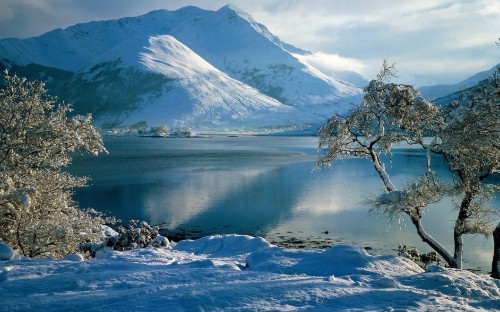 Image snow covered mountain near body of water during daytime