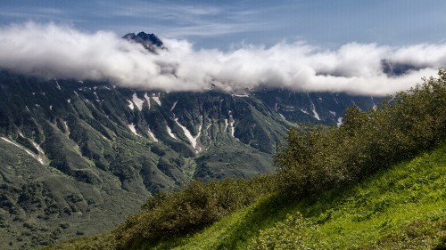 Image green grass field and mountain under white clouds during daytime