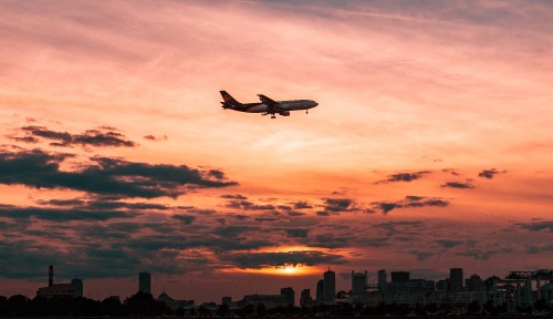 Image white airplane flying over the city during sunset