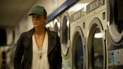 Image man in black leather jacket standing near front load washing machine