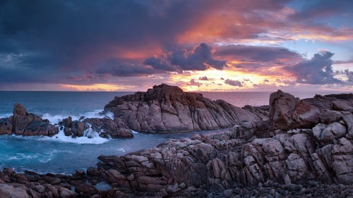 Image brown rock formation near body of water during sunset