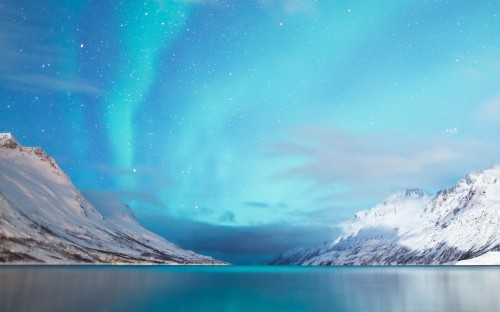 Image snow covered mountain near body of water during daytime